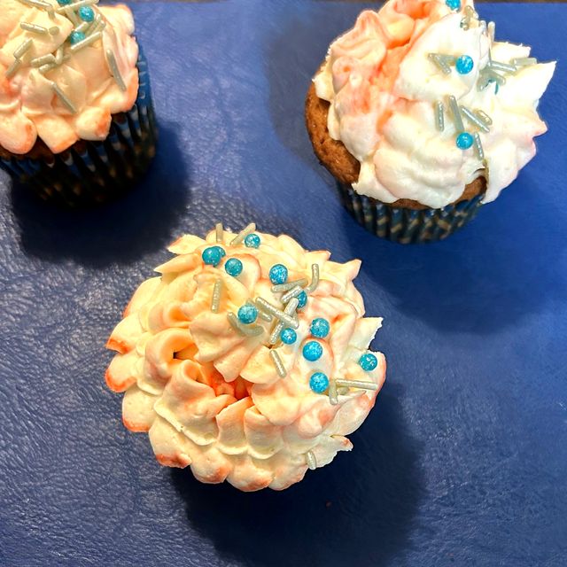 Cupcakes with white and peach frosting and blue candy pearls